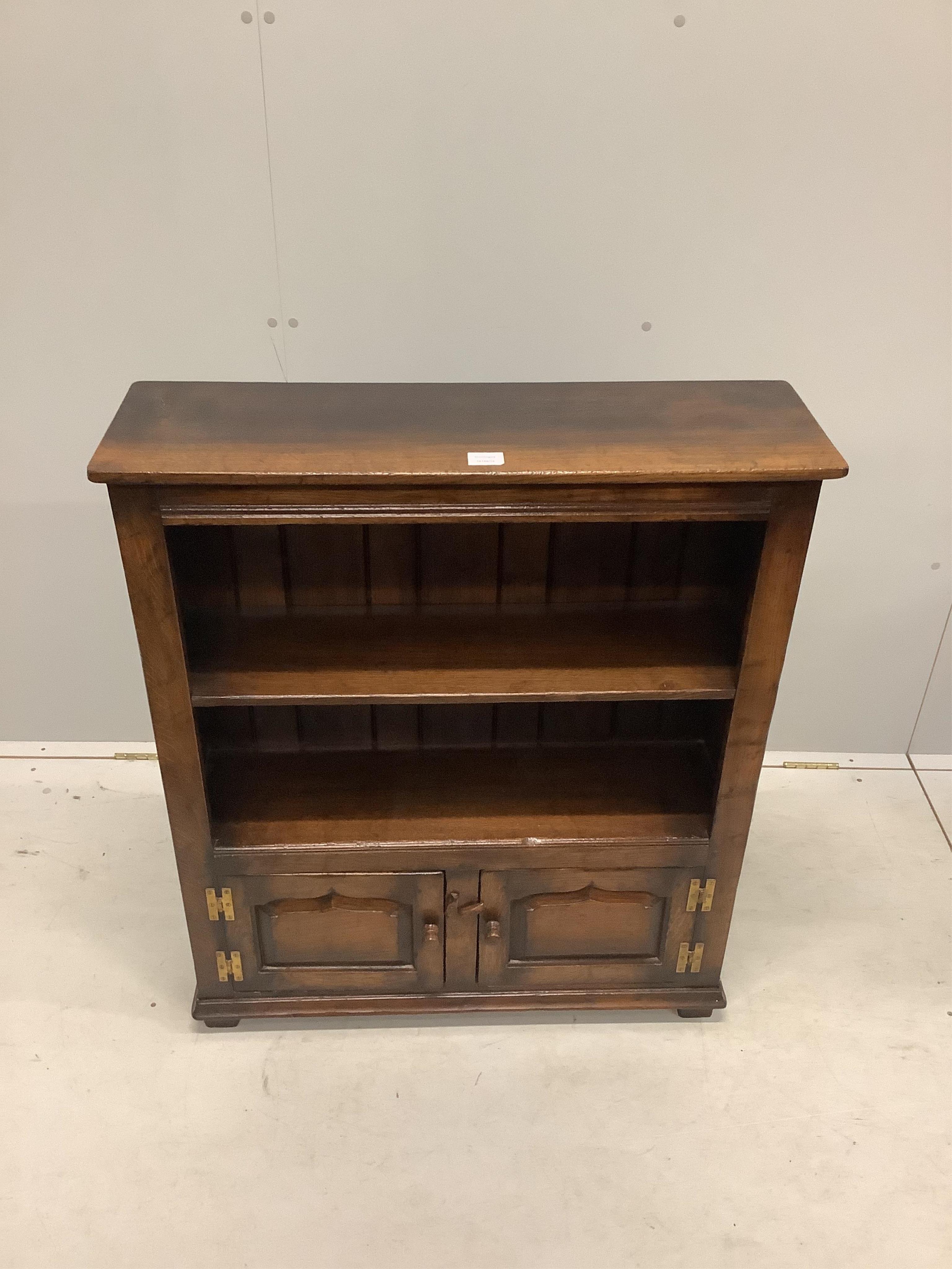 A reproduction 18th century style oak two shelf open bookcase, the base fitted with fielded panelled doors, width 84cm, depth 26cm, height 97cm. Condition - good